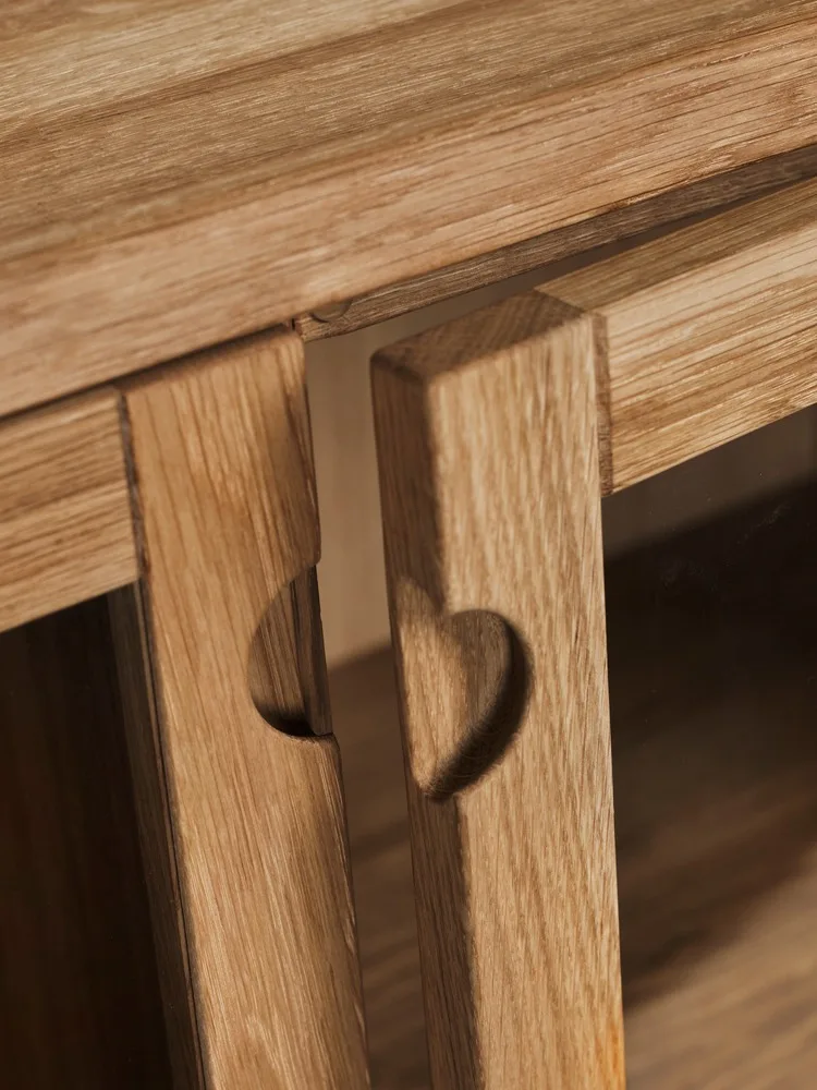 Deux panneaux en bois clair, chacun avec une découpe en forme de cœur, sur un meuble.
