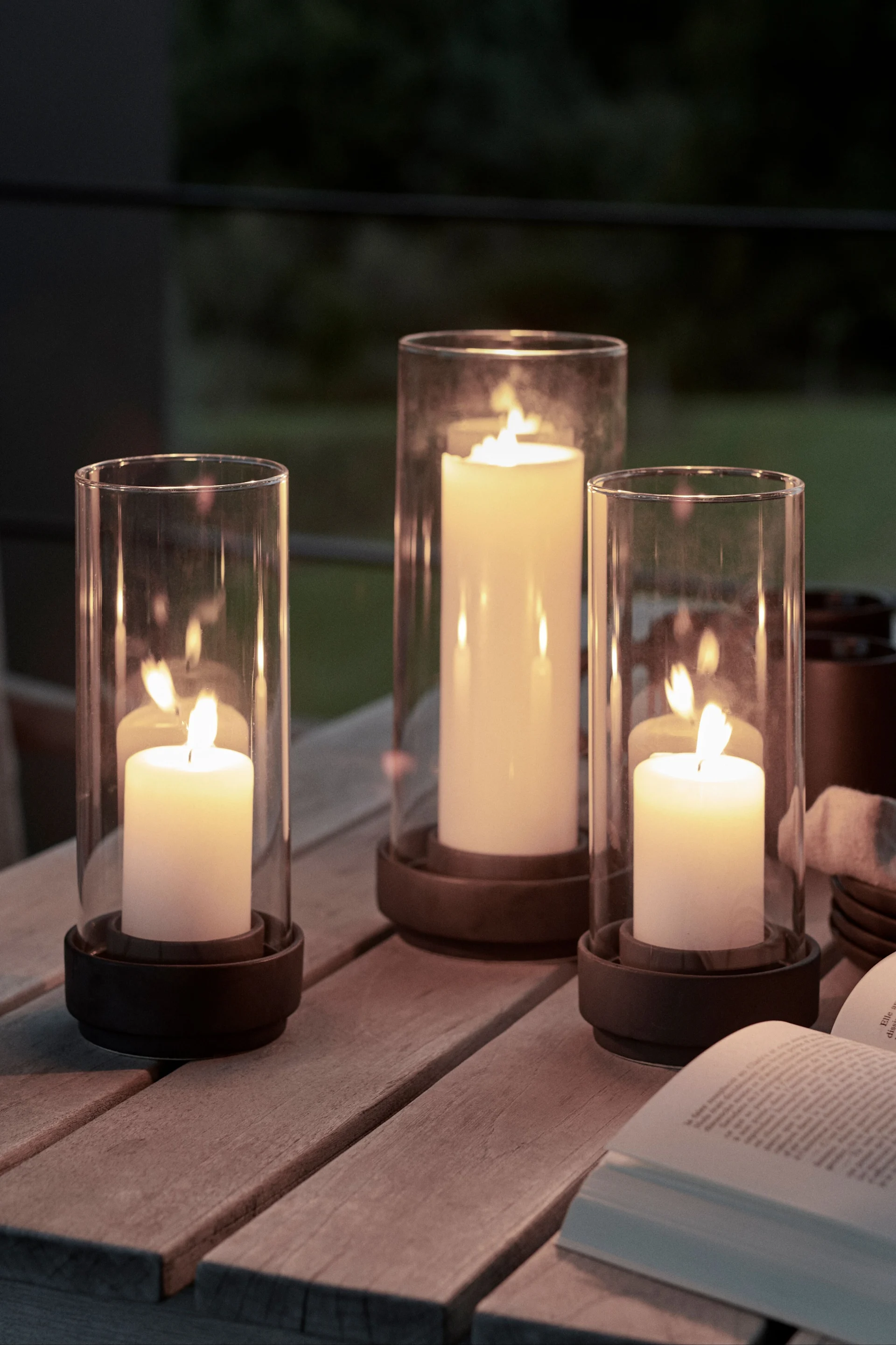 Décorez votre table de jardin avec des lanternes et des photophores d'extérieur de différentes tailles afin d'augmenter le facteur de convivialité. Les photophores Hurricane de Stelton conviennent particulièrement bien à cet effet.