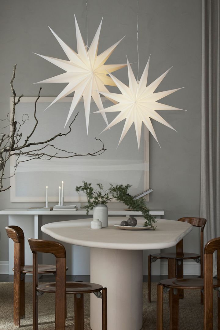 La lanterne en papier Vivi de Watt & Veke, en forme d'étoile de Noël, suspendue au-dessus d'une petite table à manger. 