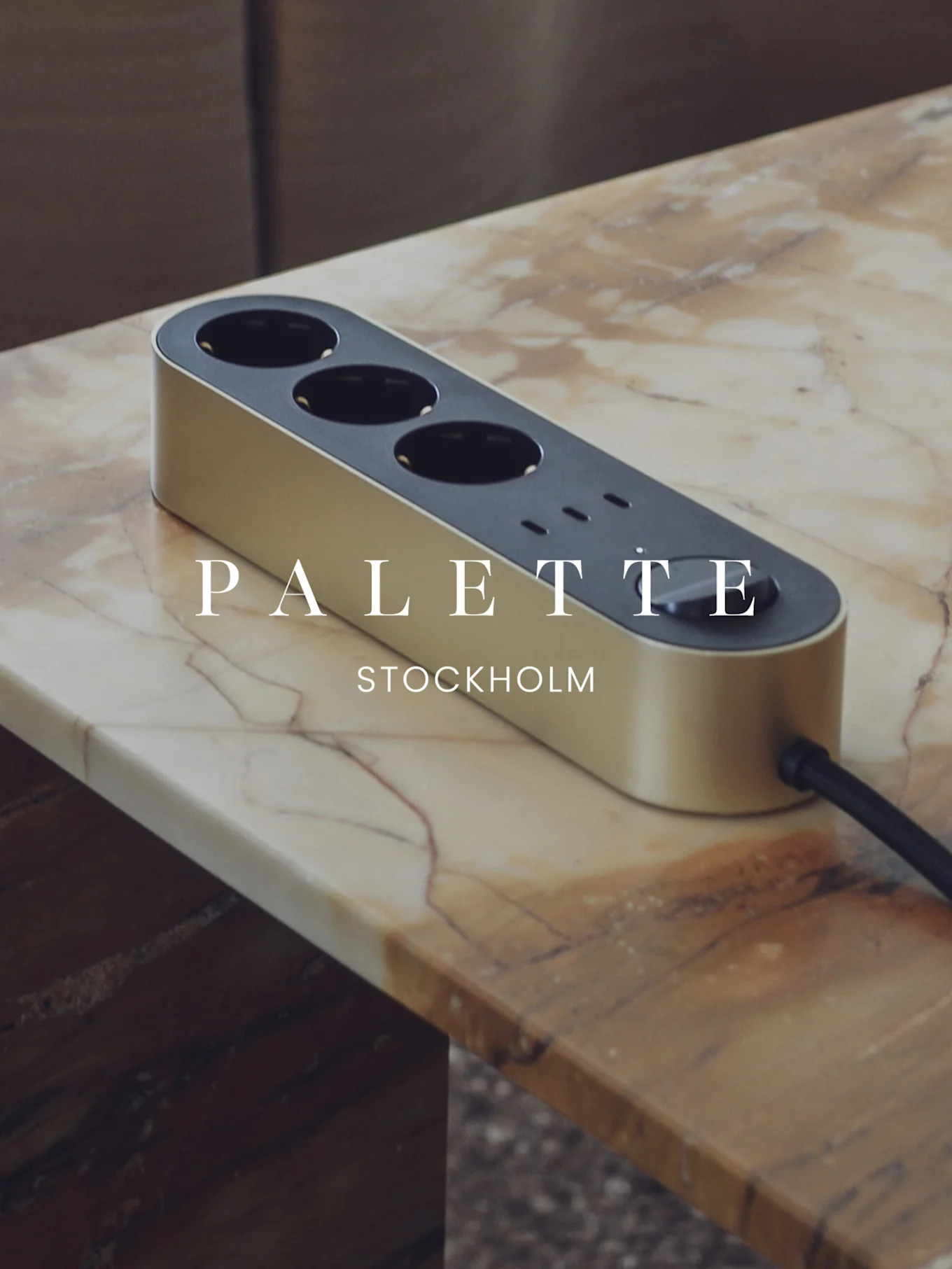 Multiprise dorée avec trois prises et trois ports USB sur une table en marbre.