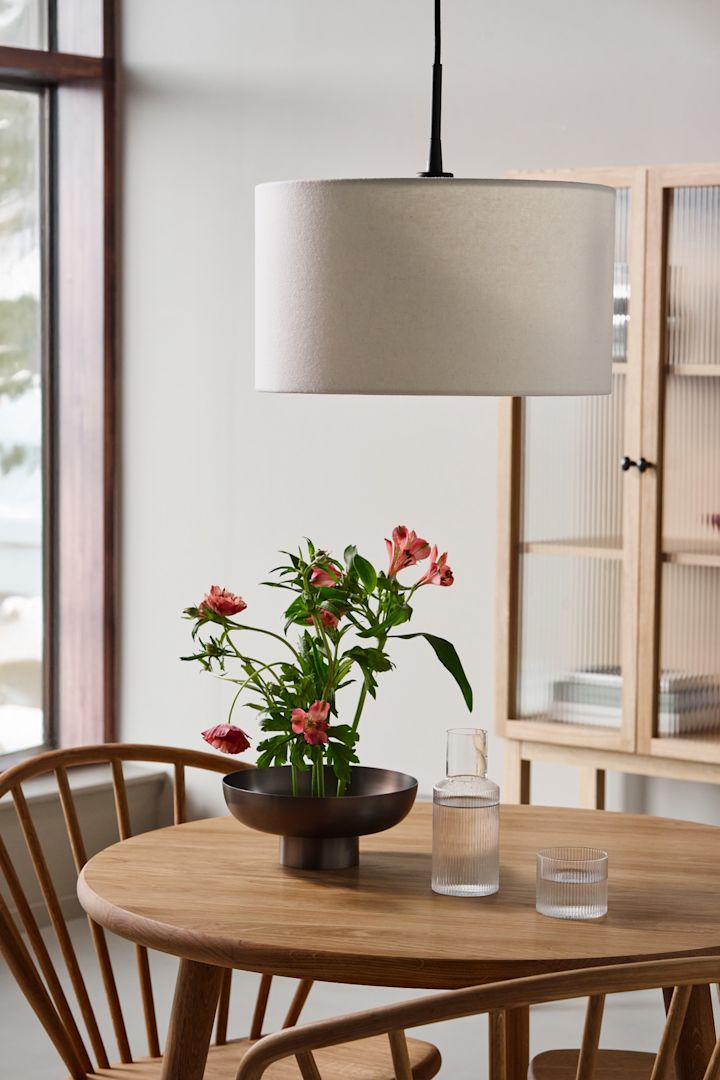 Idées d'éclairage de salle à manger pour mettre en valeur la table à manger. Ici, vous voyez la lampe suspendue Soft de Belid suspendue au-dessus d'une table à manger en bois. 