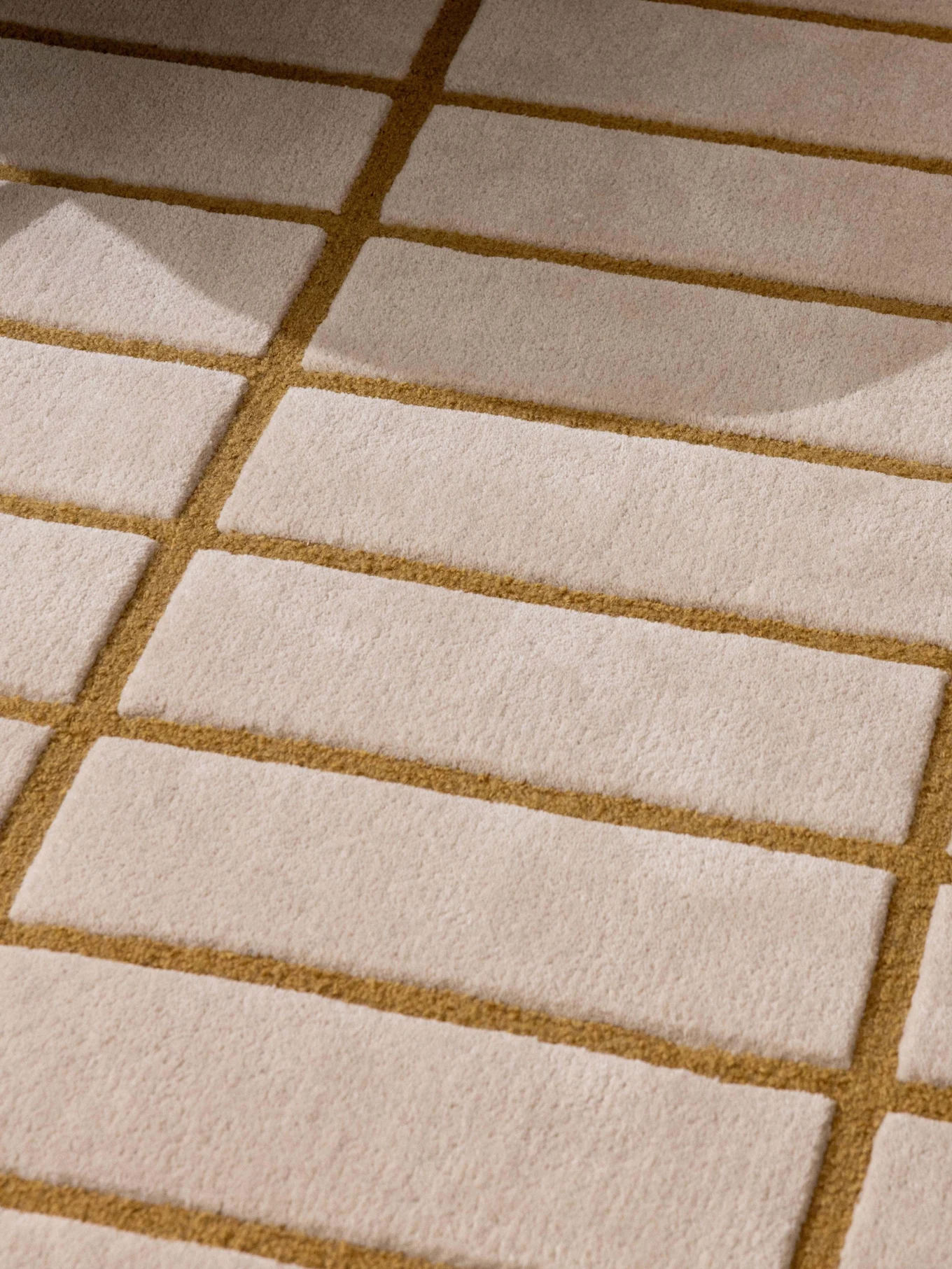 Tapis à motifs beige et marron doré, pied de fauteuil vert et plateau avec théière et tasse blanches.