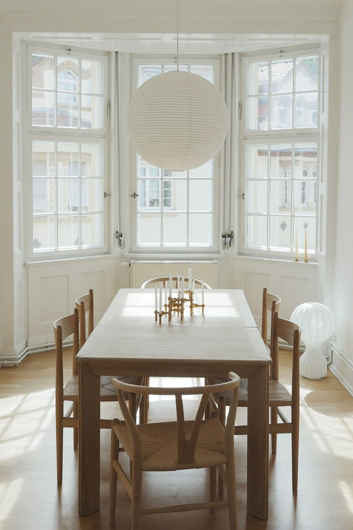 Un aménagement Lagom se caractérise par son minimalisme. Ici, vous voyez la salle à manger de @b.wohnbar avec une grande table à manger, des chaises, de hautes fenêtres et la lampe suspendue Paper rice de HAY.