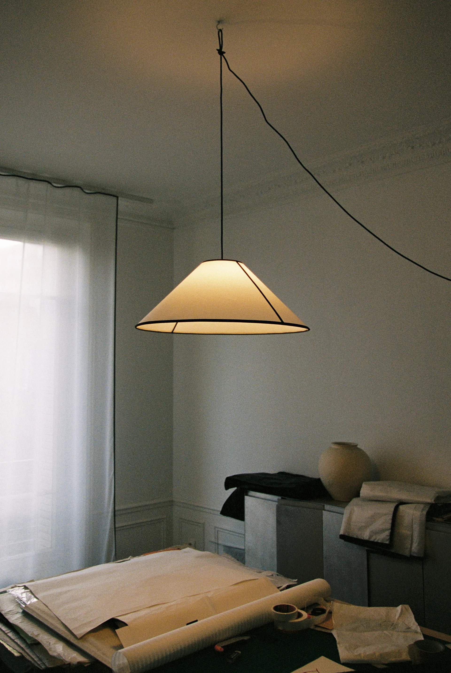 Une pièce chaleureuse avec un fauteuil crème moelleux, un lampadaire beige réglable et une étagère en bois foncé avec art et livres.