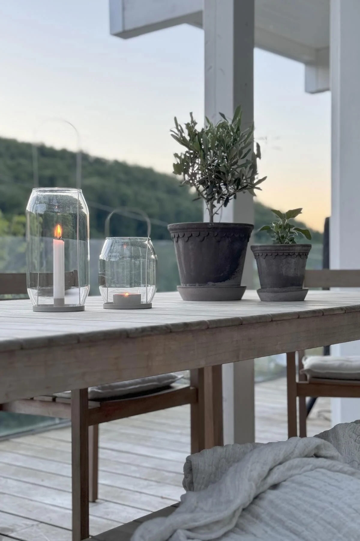 Deux pots de fleurs gris de Copenhague sont posés sur une table, à côté de deux lanternes Ernst de tailles différentes sur la terrasse de @zuhauselig.