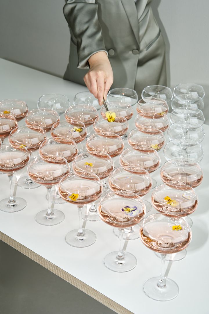 Découvrez comment organiser une fête dont tout le monde se souviendra. Ici, vous voyez une table remplie de cocktails de bienvenue servis dans les verres More coupe d’Orrefors.