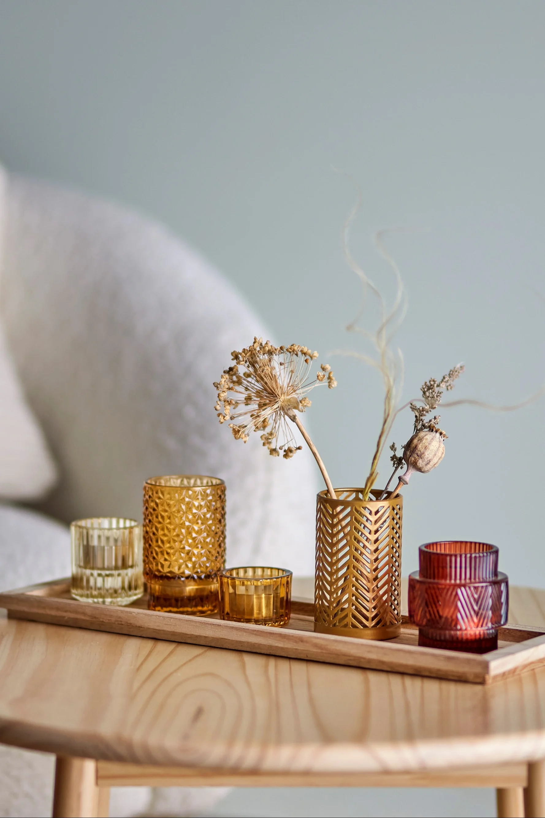 La décoration bohème parfaite : le plateau Sanga avec des photophores aux tons jaunes et rouges de Bloomingville sur une table de salon.