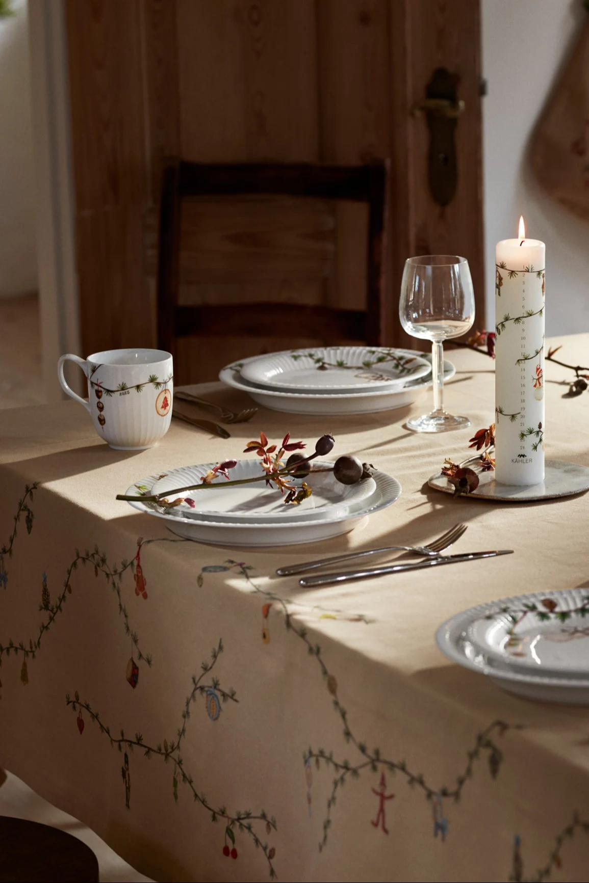 Une table festive dressée avec la vaisselle de Noël et la nappe Hammershøi de Kähler.