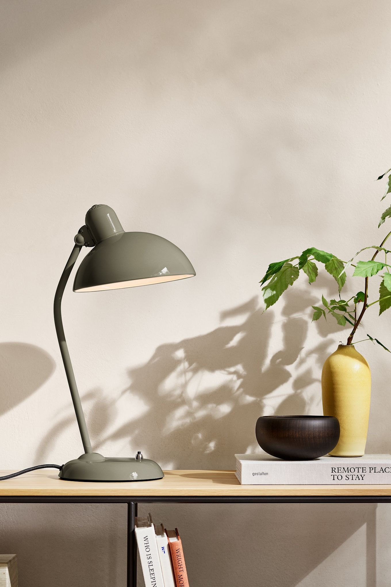 Les tendances en matière de couleurs d'intérieur pour 2025 comprennent une nuance naturelle de vert olive. Ici, la lampe Kaiser Idell de Fritz Hansen est posée sur un buffet. 
