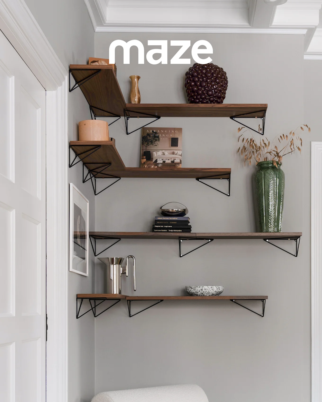 Portemanteau blanc en forme d'arbre avec des boutons en bois dans une chambre d'enfant avec un lit bébé et des jouets. La marque 'maze' est visible.