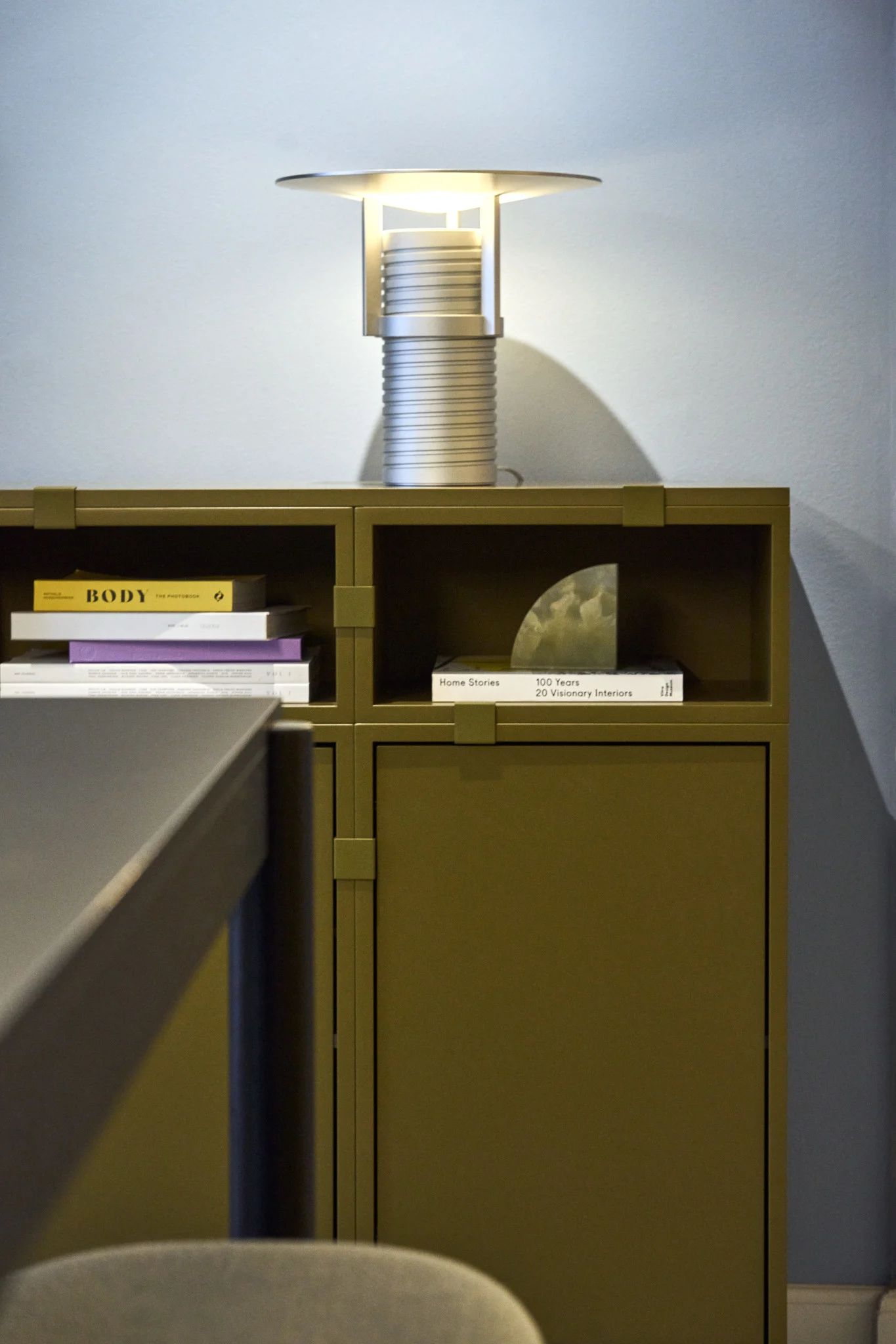 Une étagère verte, construite à partir de la collection Stacked, avec la lampe de table Set argentée sur le dessus, le tout de Muuto.