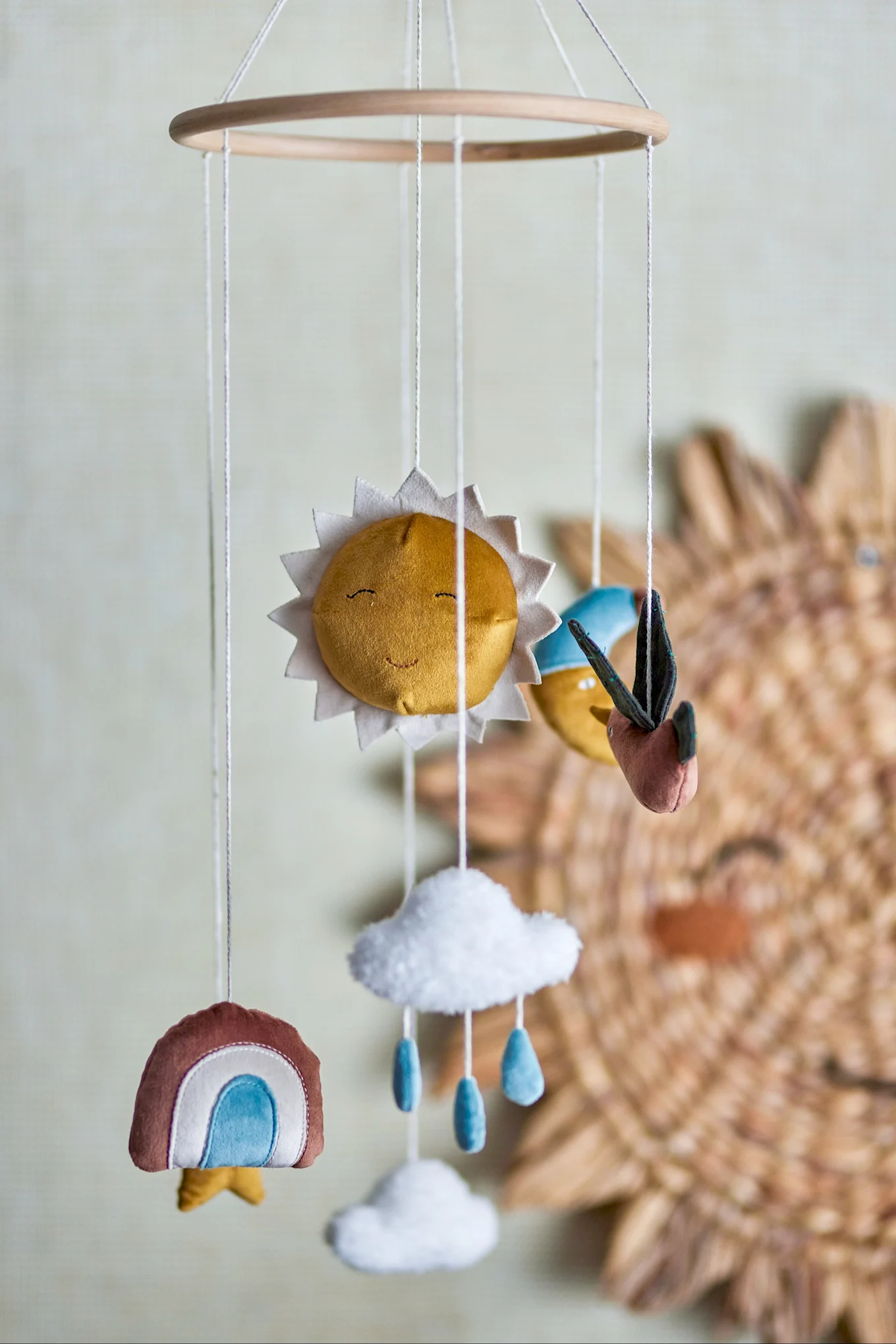 Le mobile Vigge de Bloomingville est composé de pendentifs en tissu en forme de soleil, d'arc-en-ciel et de nuages, ce qui en fait un super cadeau pour la baby shower.