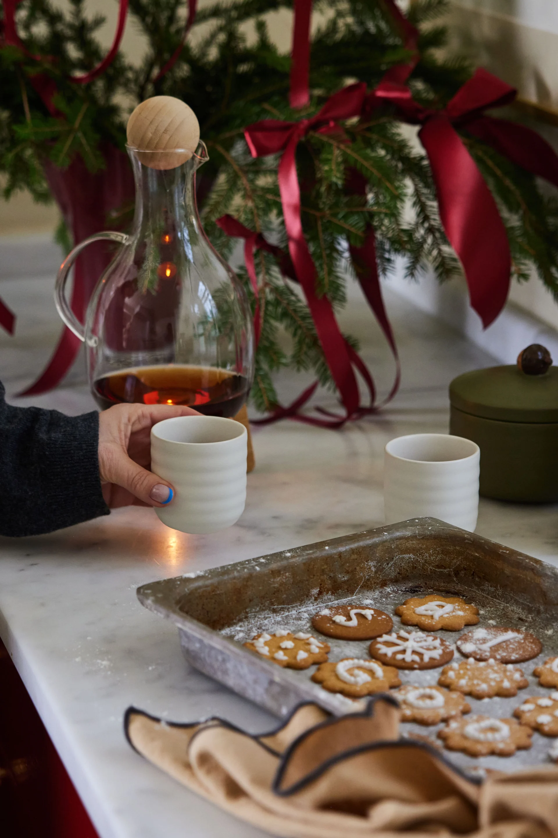 En Suède, Noël est traditionnellement célébré avec des pepparkakor et du glögg. Ici, un plateau de biscuits est posé sur le comptoir de la cuisine, accompagné de deux tasses et d'une cruche de glögg.