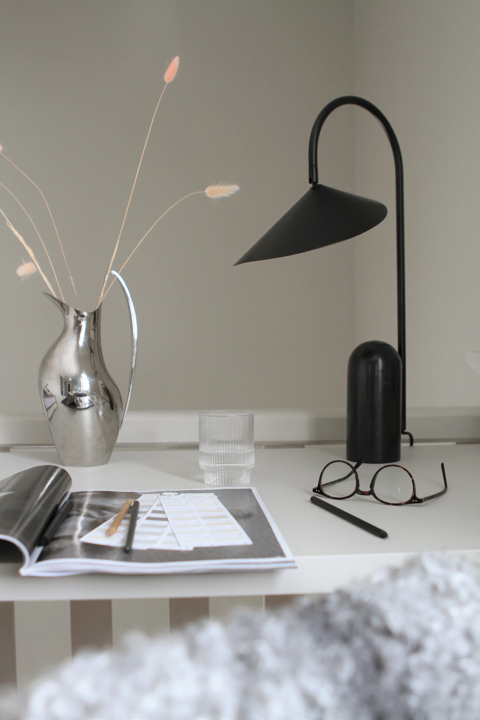 Lampes scandinaves : la lampe de table noire Arum de Ferm Living trône sur un bureau.