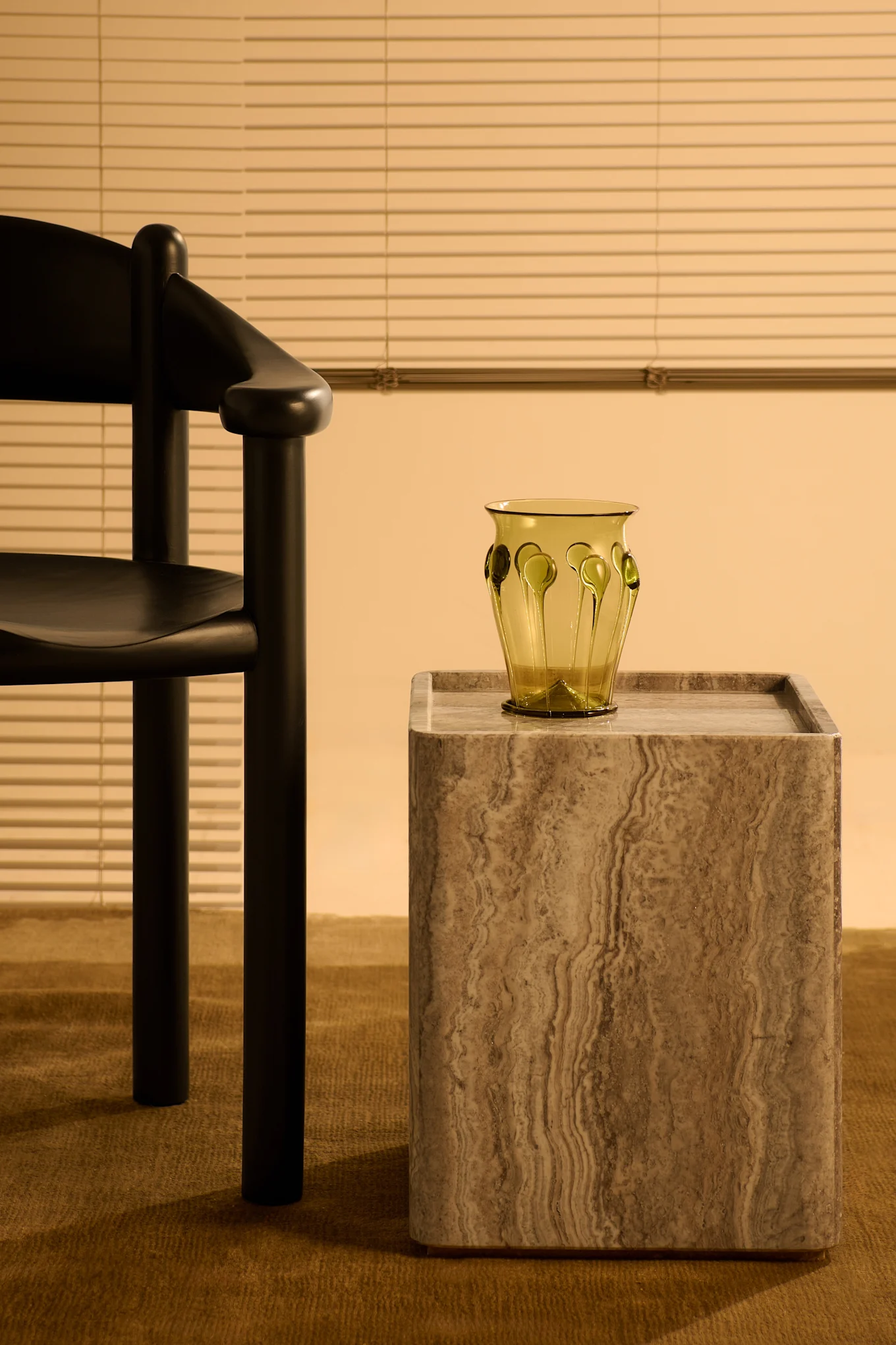 Table d'appoint en travertin de Gubi et chaise en pin noir de Gubi, tout à fait adaptées aux tendances de la décoration intérieure 2025. 