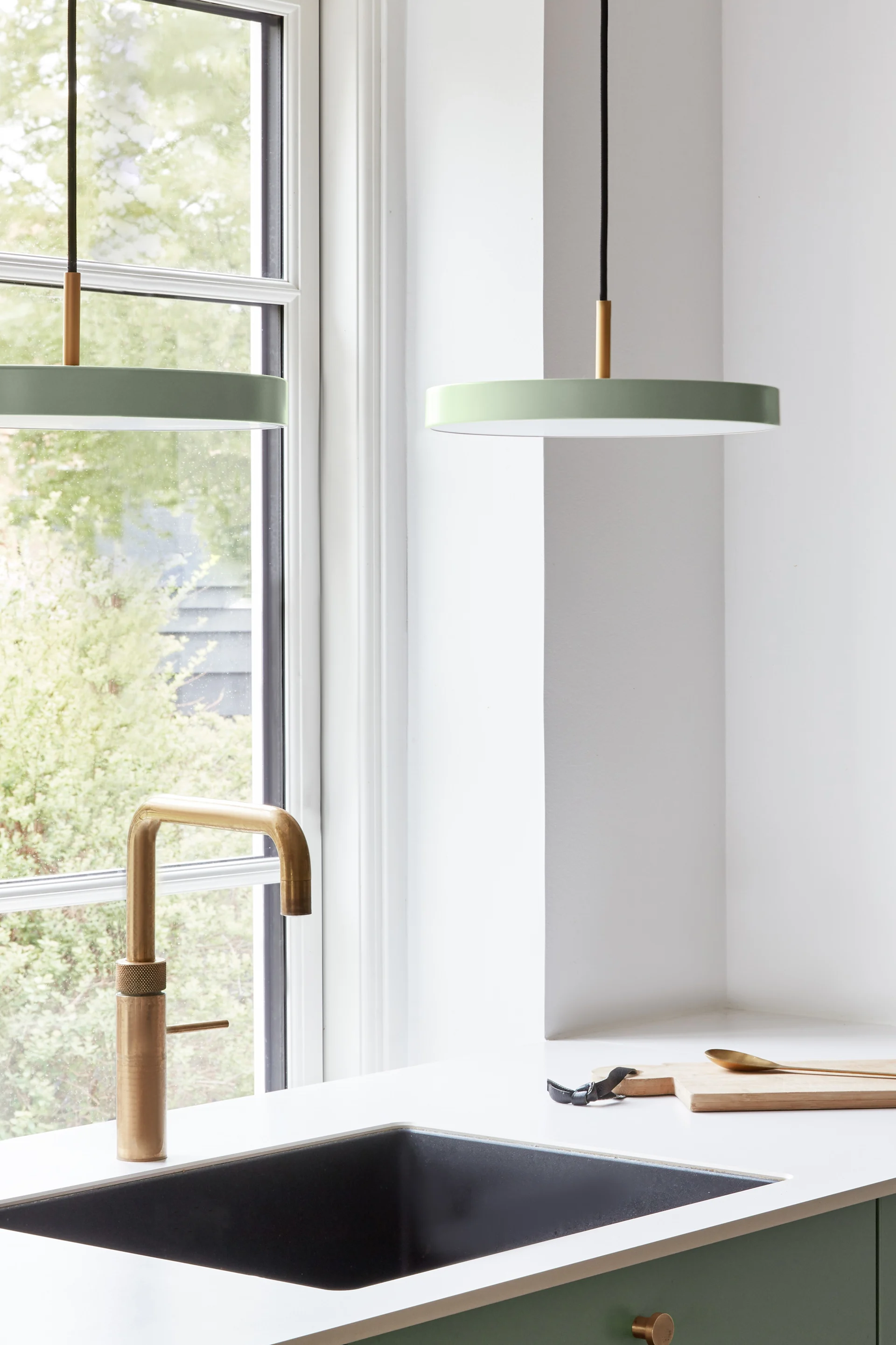 Lampes scandinaves : la mini suspension verte Asteria d'Umage est suspendue au-dessus d'un coin cuisine avec évier.
