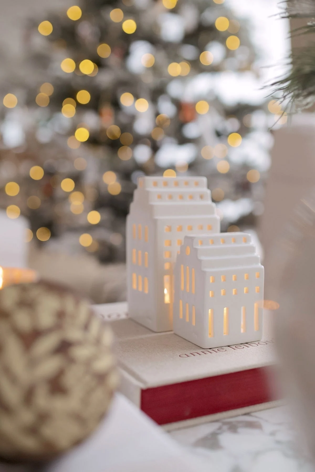 Deux maisons lumineuses de la collection Urbania de Kähler sont placées sur un livre devant un sapin de Noël, dans la maison de @widveyshome.