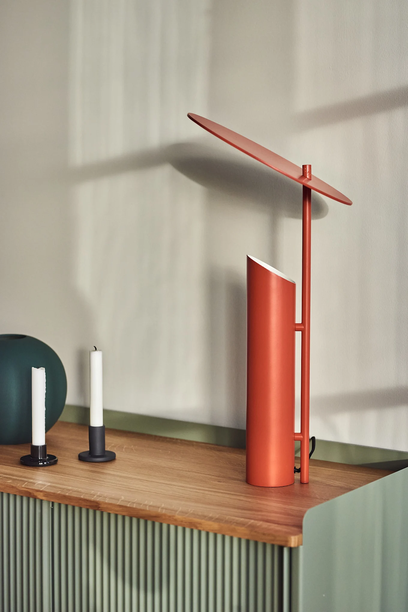 Sur une commode se trouve la lampe de table Reflect rouge de Verpan, conçue par Verner Panton.