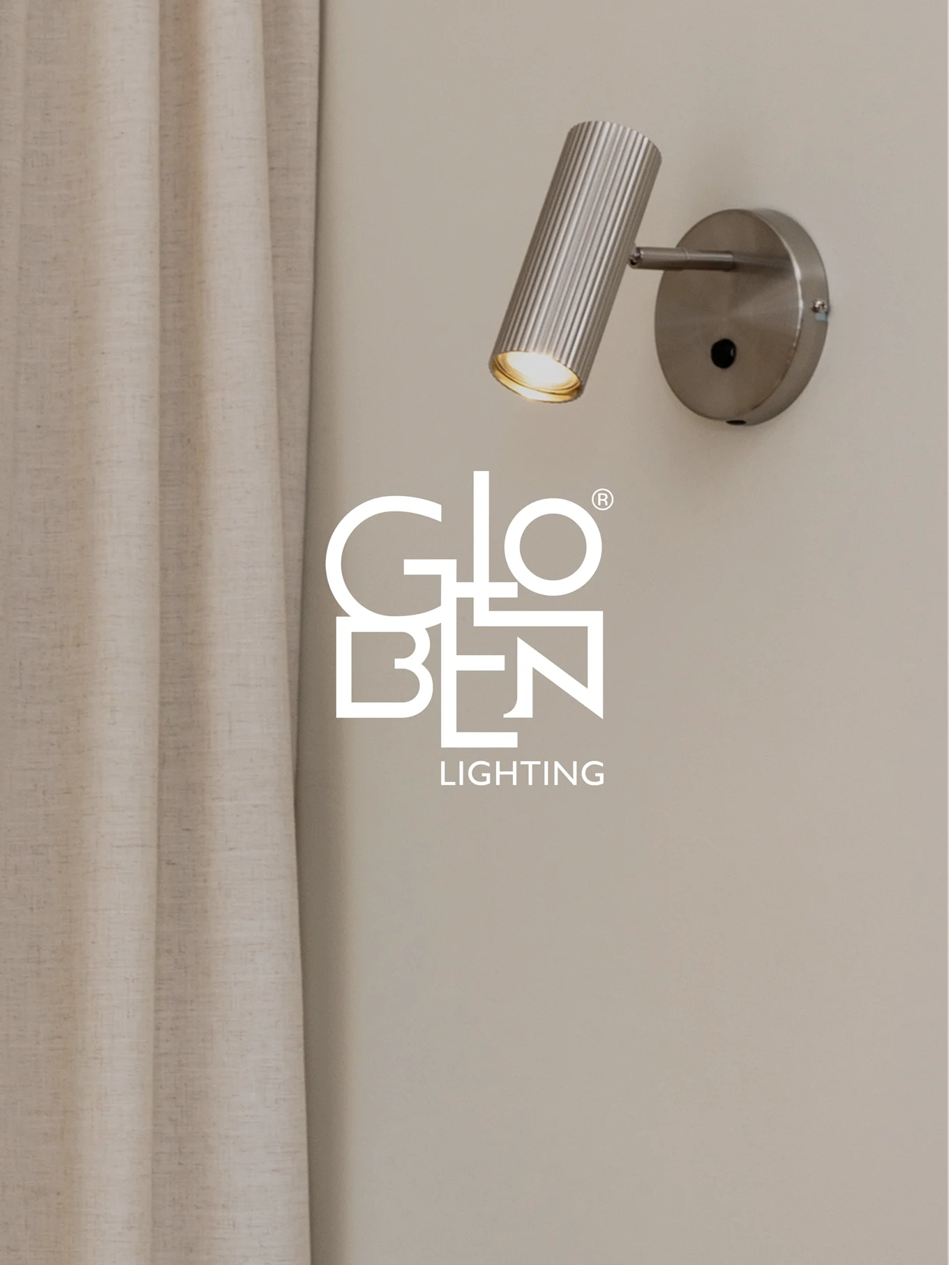 Un spot mural en métal brossé et nervuré avec une lumière chaude, à côté d'un rideau clair, avec le logo Globen Lighting.