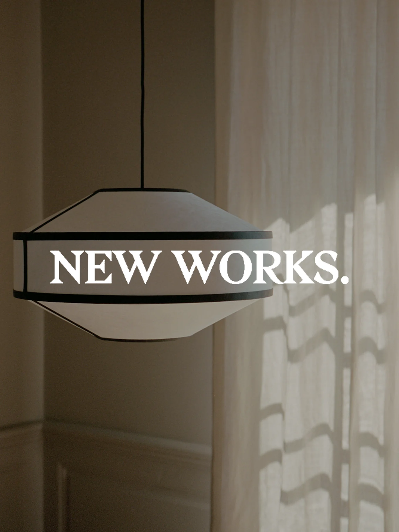 Un large luminaire suspendu blanc à bord foncé est accroché, avec le texte 'NEW WORKS.' superposé. Le soleil projette des ombres sur un rideau.