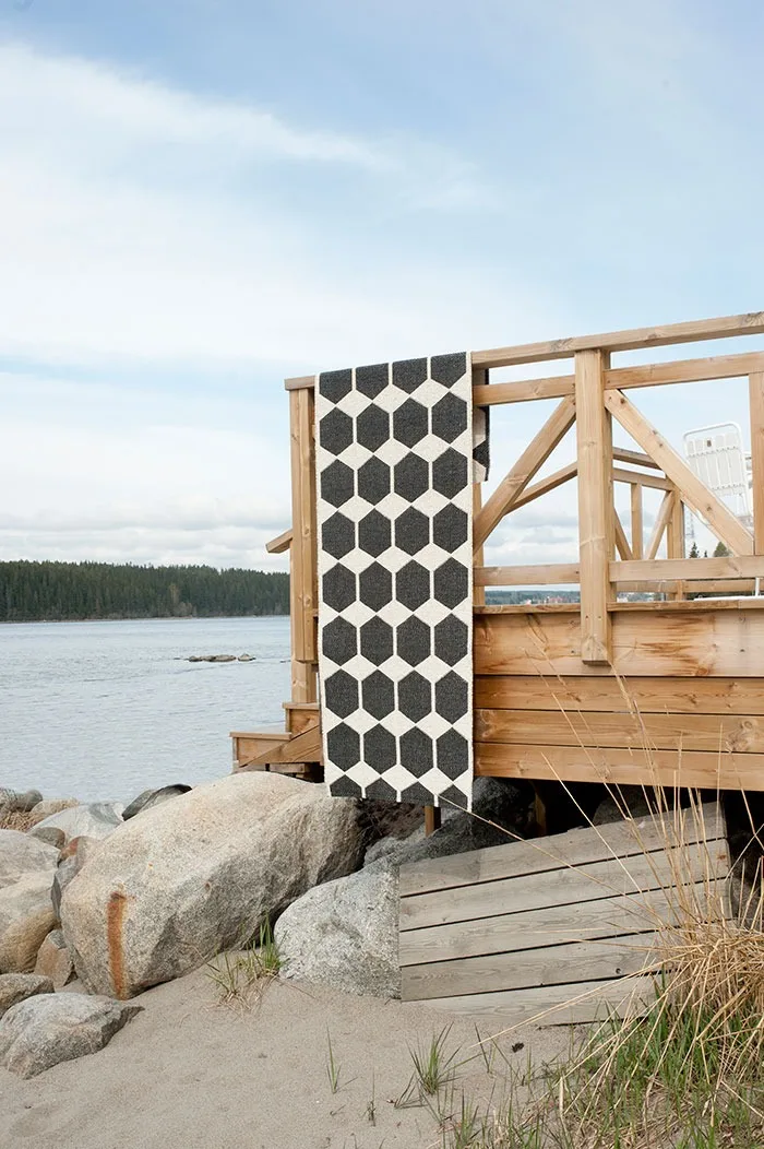 Tapis d'extérieur : nettoyez votre tapis d'extérieur à intervalles réguliers et suspendez le tapis Anna de Brita Suède en noir que vous voyez ici, par exemple au-dessus de la balustrade du balcon pour le faire sécher.