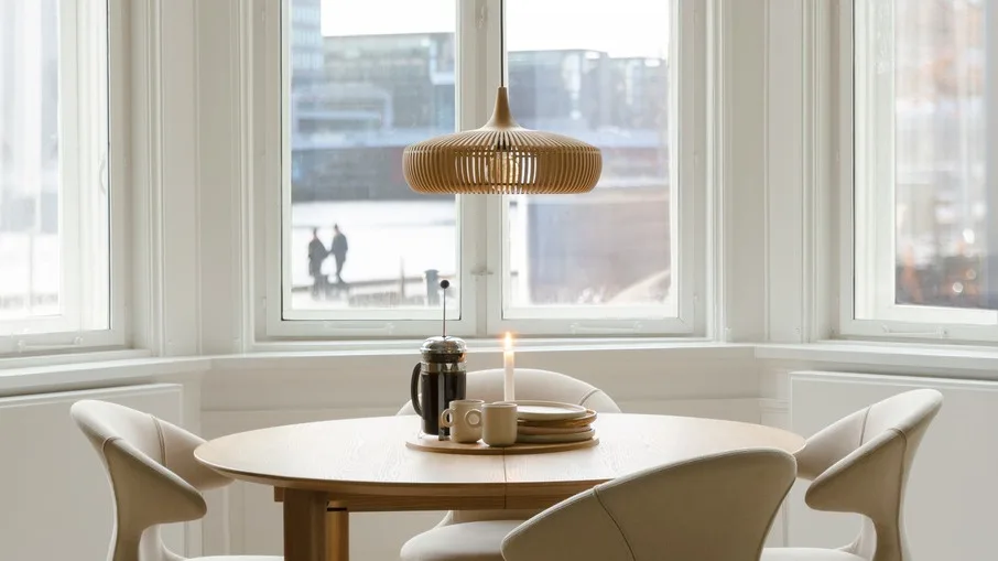 Lagom : une salle à manger à la décoration minimaliste avec de nombreuses fenêtres et la lampe suspendue Clava Dine Wood d'Umage.