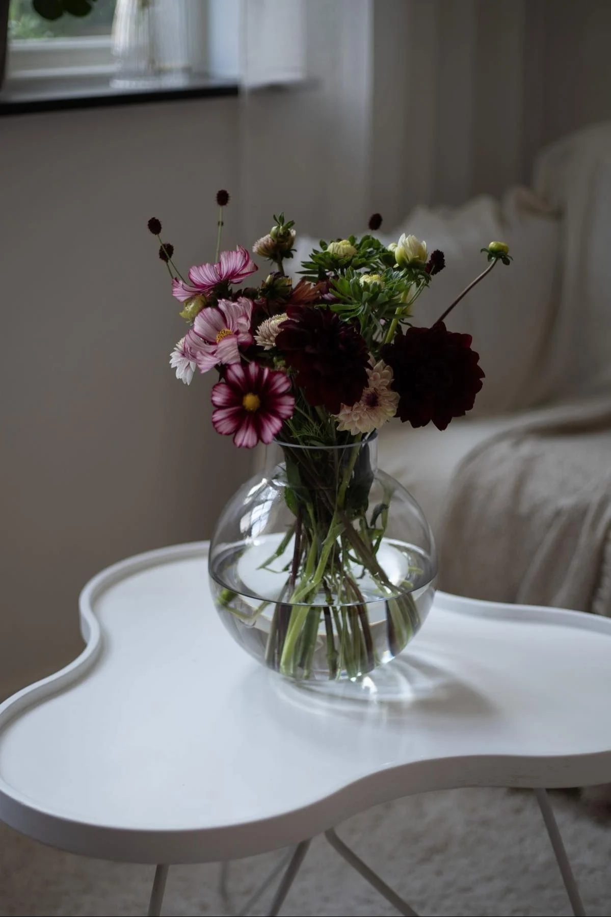 Le vase en verre d'Ernst, que l'on voit ici sur la table à fleurs de Swedese dans la maison de @norregardnr9, est un excellent cadeau pour la fête des mères avec un magnifique bouquet rose et violet.