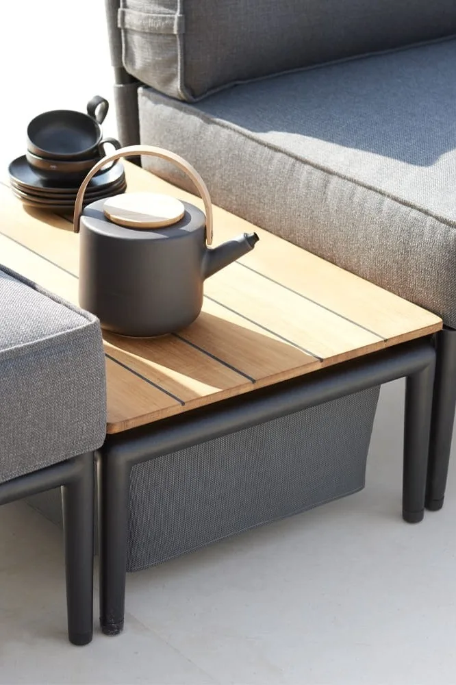 La table basse Conic de Cane-line ne sert pas seulement de surface de rangement, elle offre également un espace de rangement pour les couvertures ou les coussins et compte donc à juste titre parmi les tendances 2025 en matière de meubles de jardin.