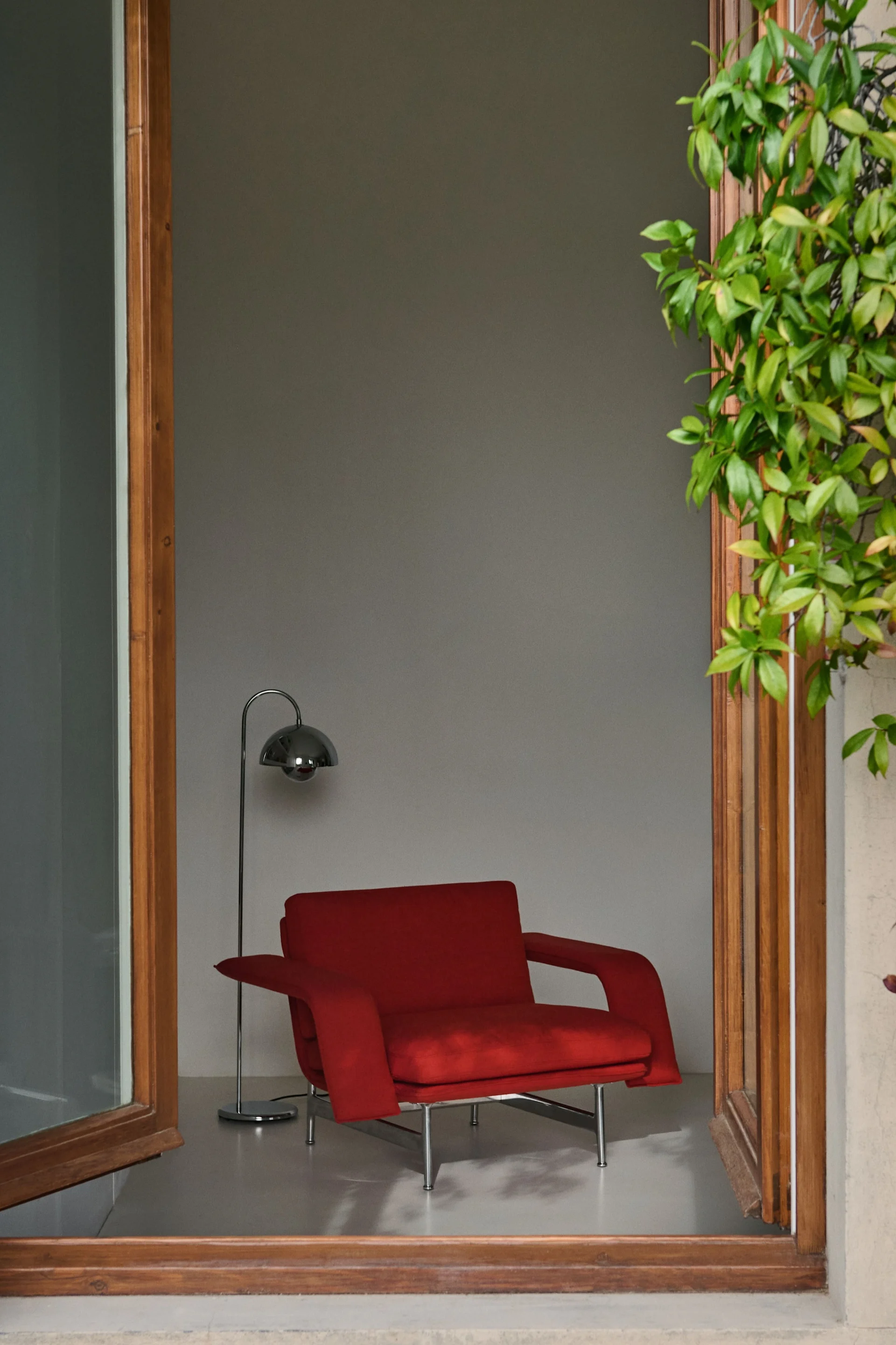 Les années 60 et 70 reviennent en force dans les tendances d'intérieur de l'automne 2025. Ici, la chaise longue rouge Meantime de &tradition se trouve dans une fenêtre ouverte.