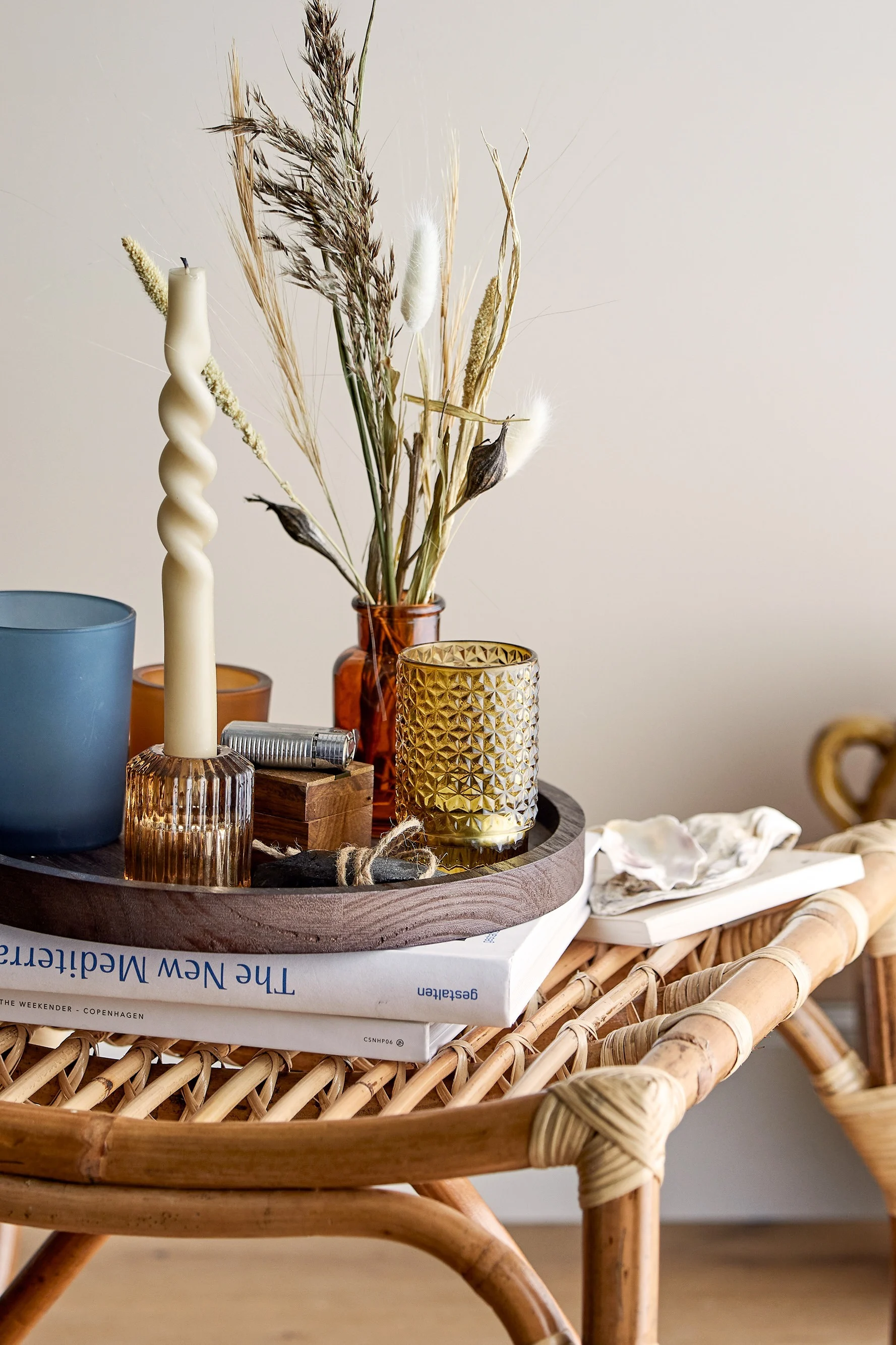 Sur une table basse de style bohème se trouve un plateau avec des photophores de Bloomingville.