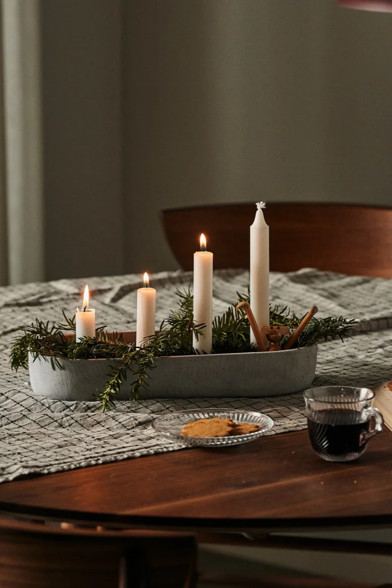 Décoration de Noël scandinave : ici, le porte-bougie Marb de House Doctor est décoré de branches de sapin et posé sur une table.