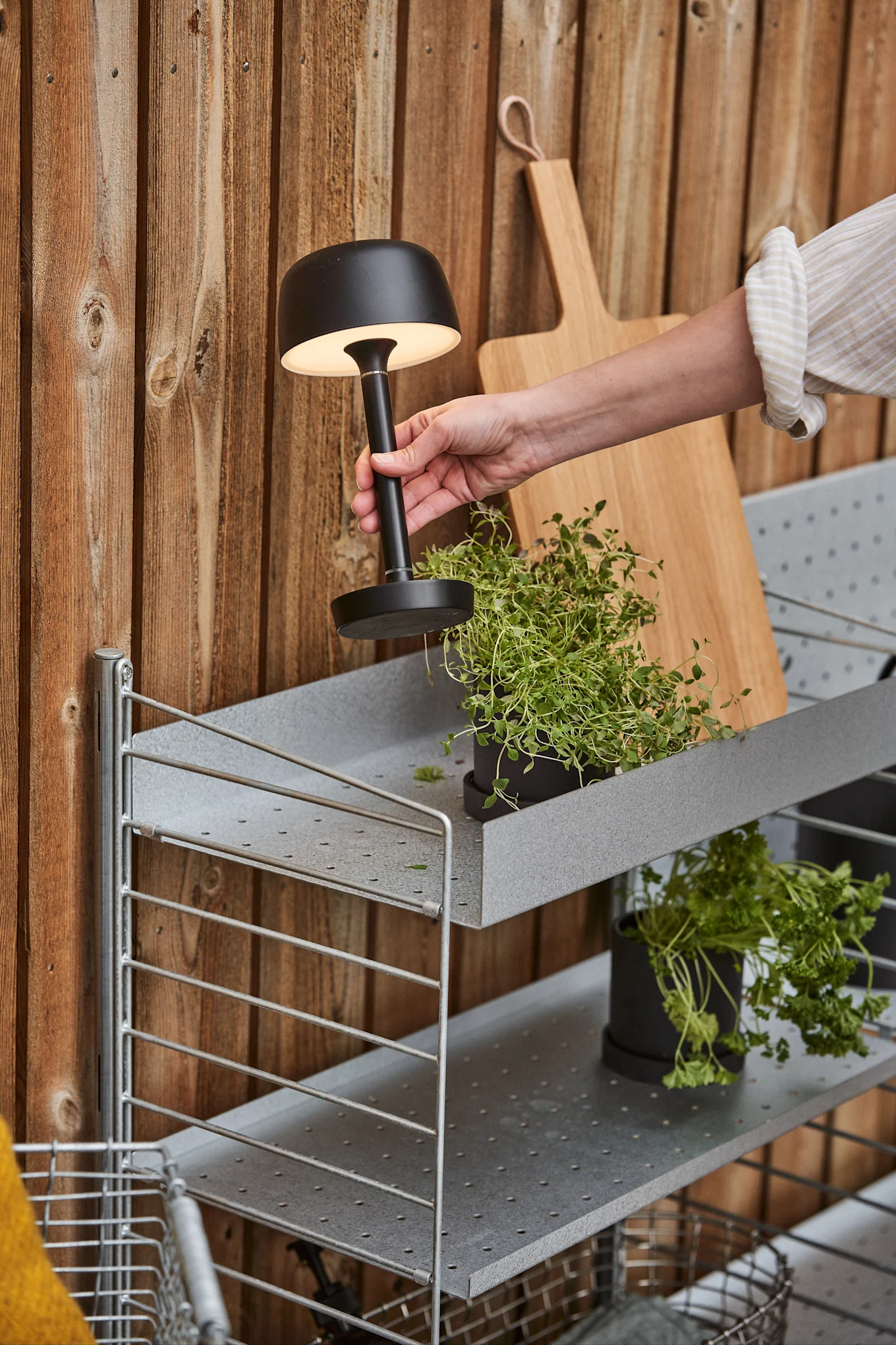 La lampe rechargeable Halo noire de Scandi Living est placée à l'extérieur sur une étagère.