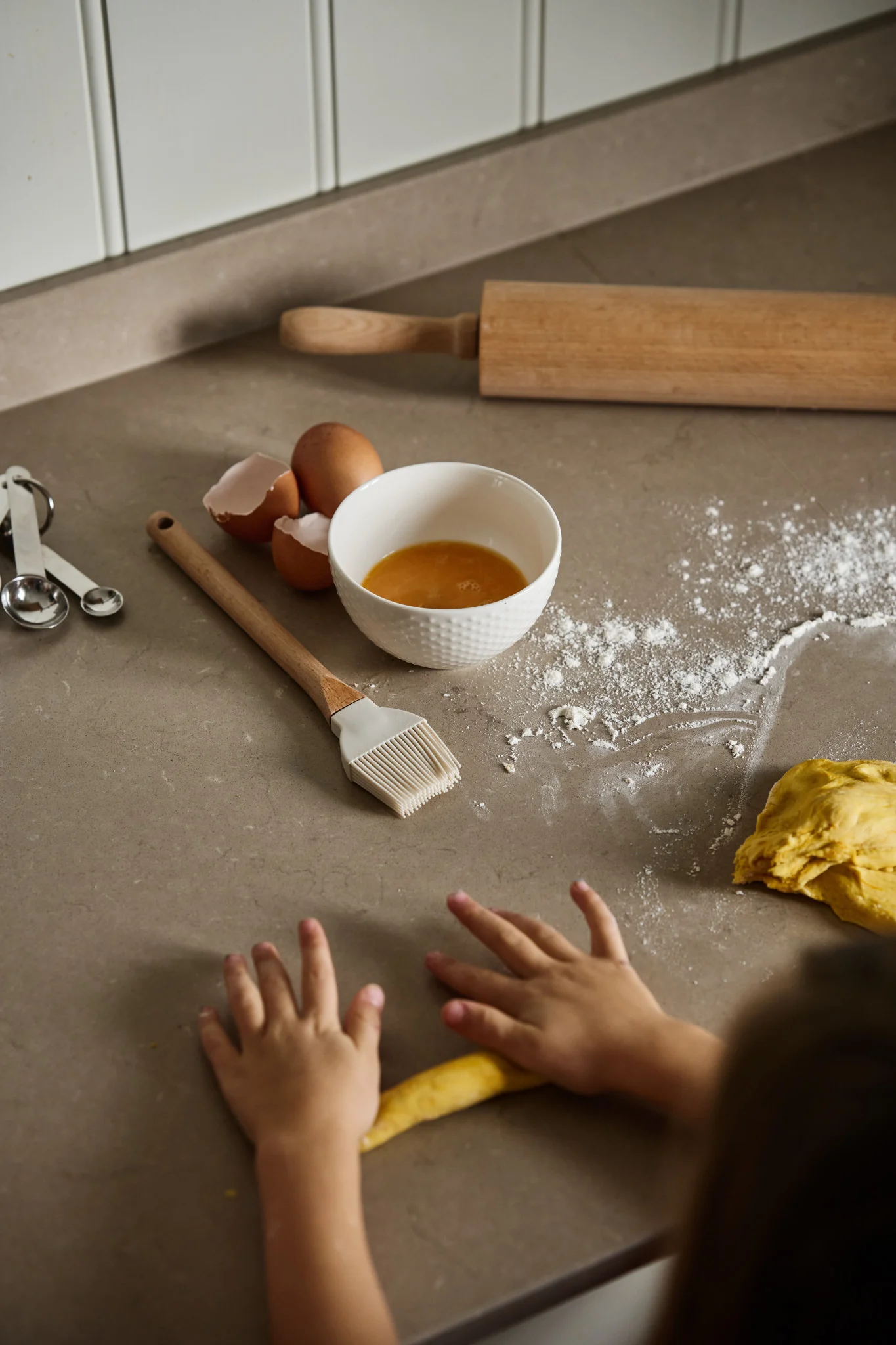 Une paire de mains d'enfants étalant la pâte à lussekatter sur un plan de travail dans la cuisine : une gourmandise parfaite pour votre fête de Noël suédoise.