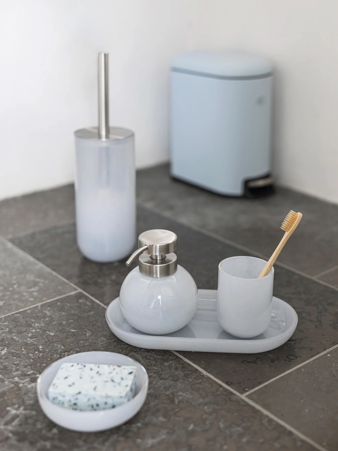 Ensemble de salle de bain bleu clair: brosse WC, distributeur de savon, gobelet avec brosse à dents en bambou, porte-savon et poubelle à pédale.