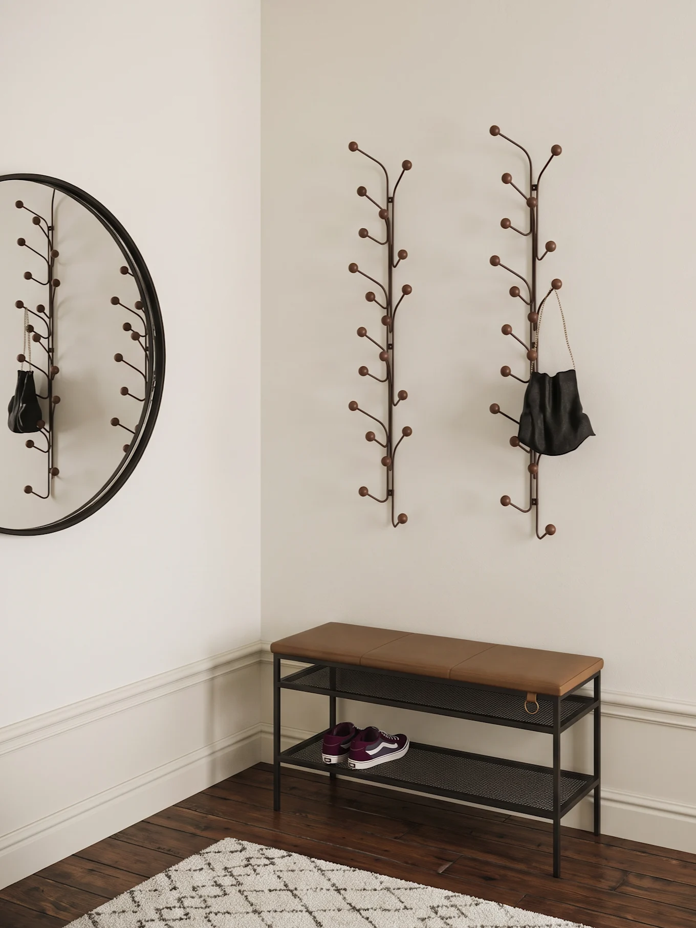 Entrée avec deux porte-manteaux en forme de branche, un miroir rond, un banc marron avec des baskets violettes et un tapis.