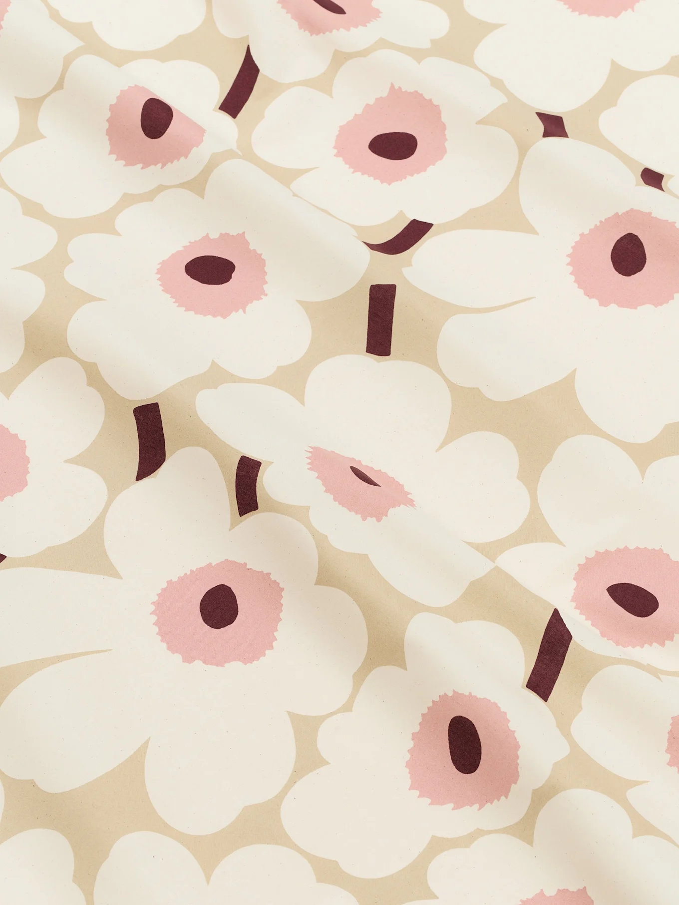Gros plan d'un tissu beige clair orné de grandes fleurs blanches stylisées aux centres roses et aux tiges bordeaux foncé.
