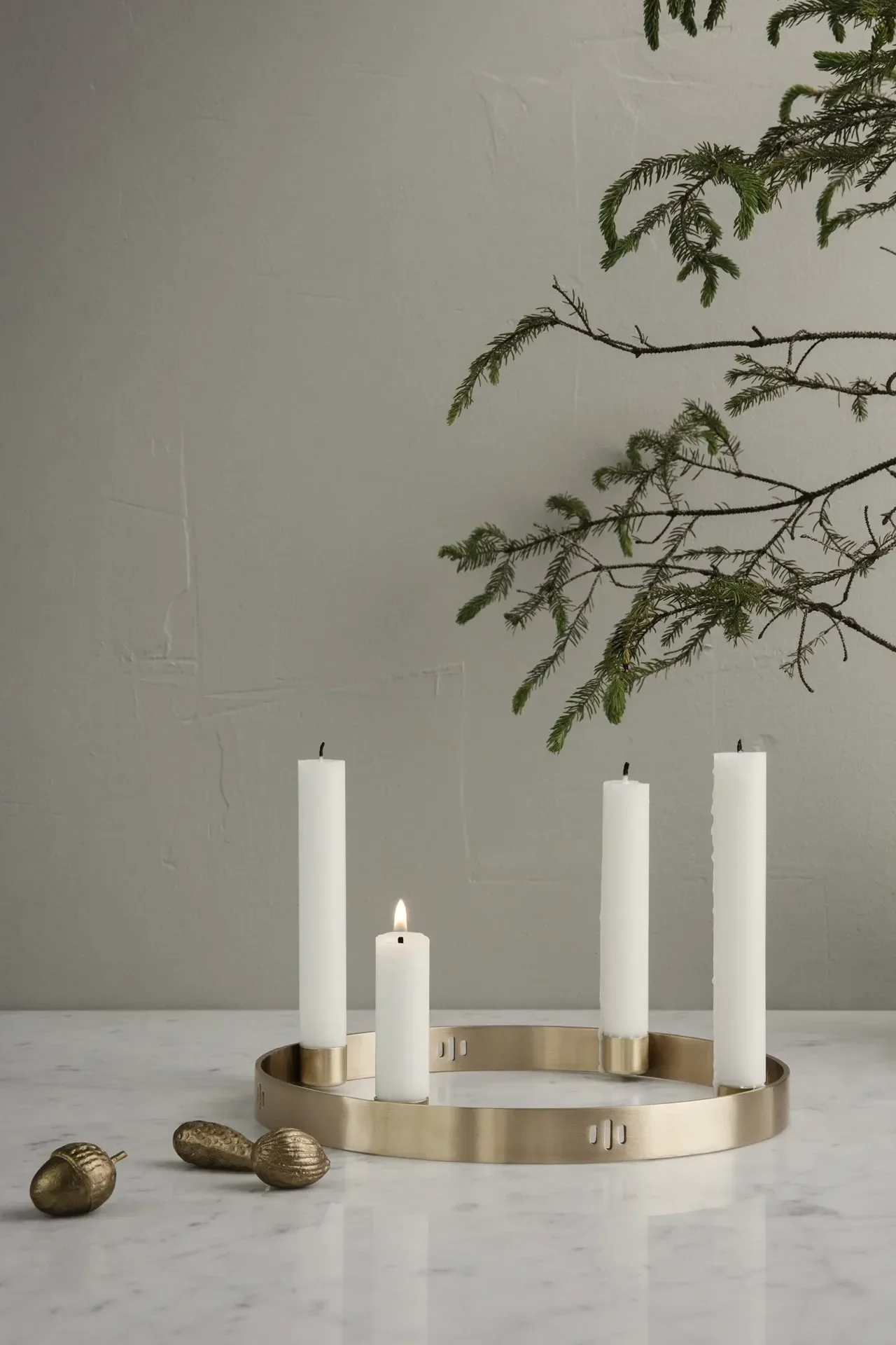 Dans une ambiance sobre, le bougeoir Circle en laiton de Ferm Living trône sur une table.