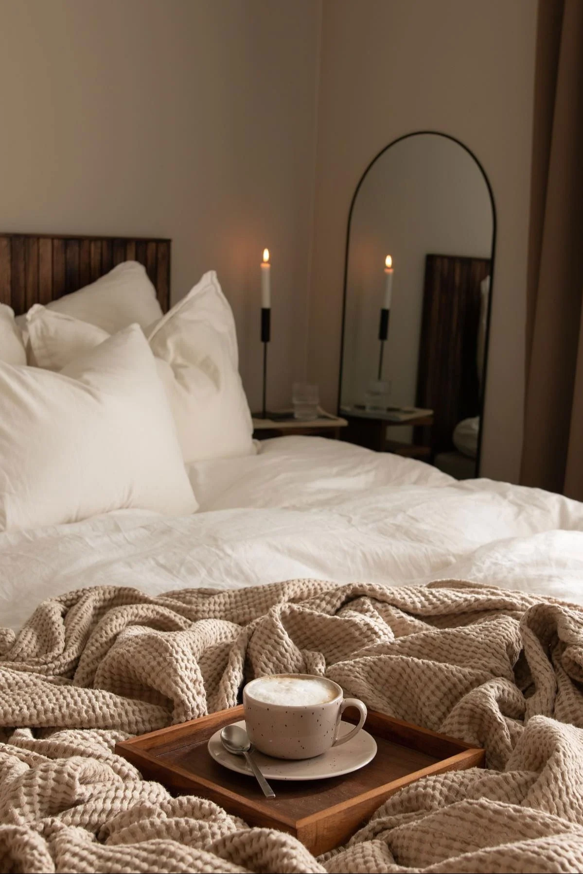 Lagom : la chambre à coucher confortablement aménagée de @joanna.avento avec un miroir, une bougie, un couvre-lit et une tasse Freckle de Scandi Living avec du café.