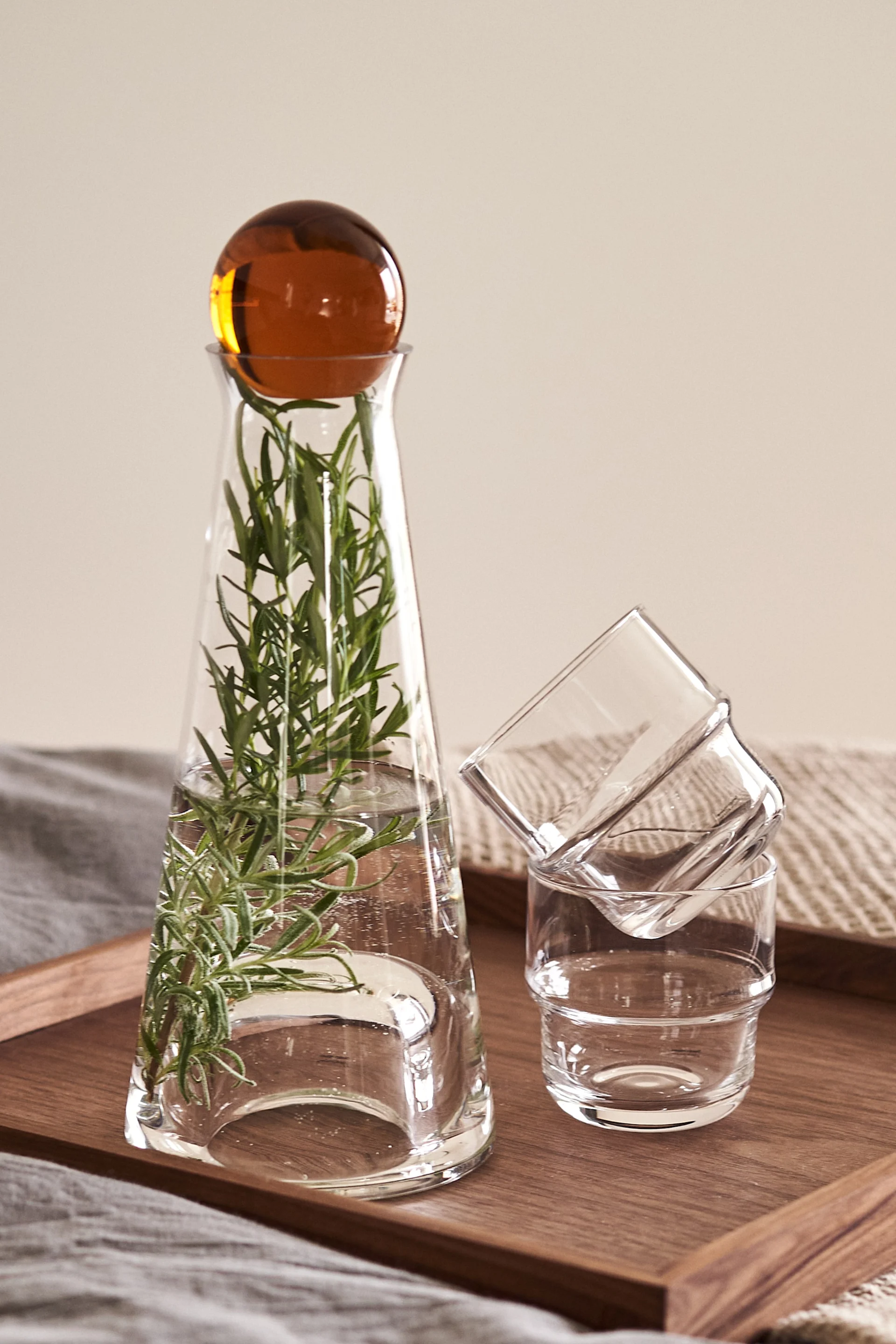 Ici, vous voyez la carafe Fia avec un bouchon ambré et un brin de romarin avec les verres NM&, tous de Design House Stockholm. 