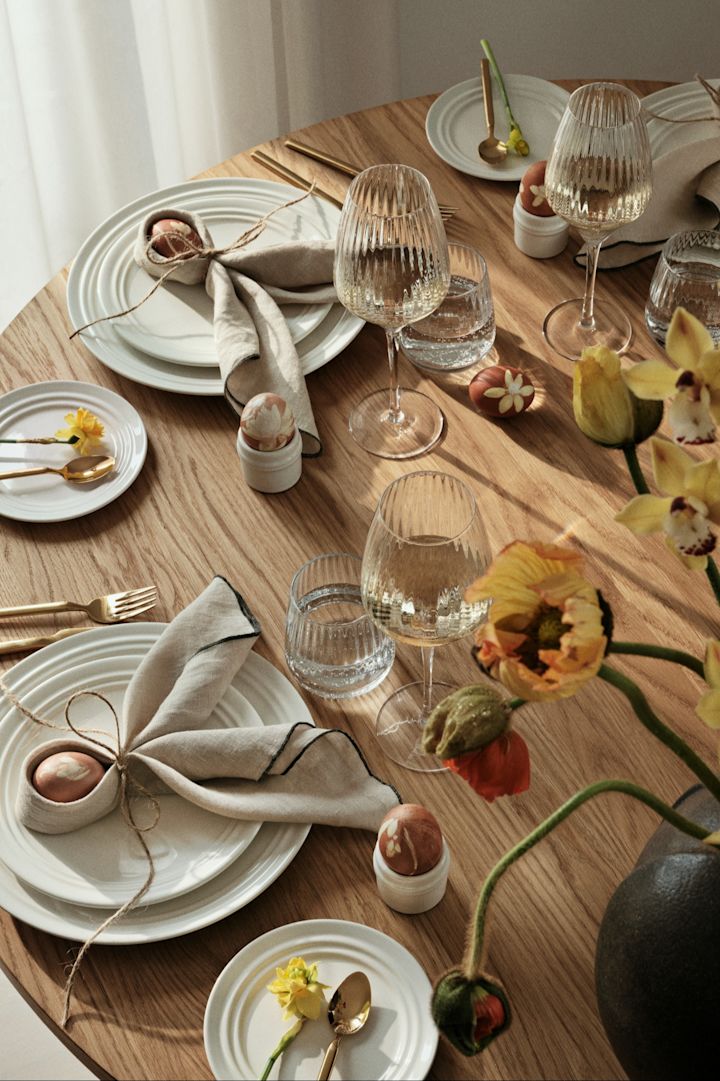 La table à manger est garnie de vaisselle, de verres et de couverts de Broste Copenhagen. Les serviettes de table sont pliées en forme d'oreilles de lapin.