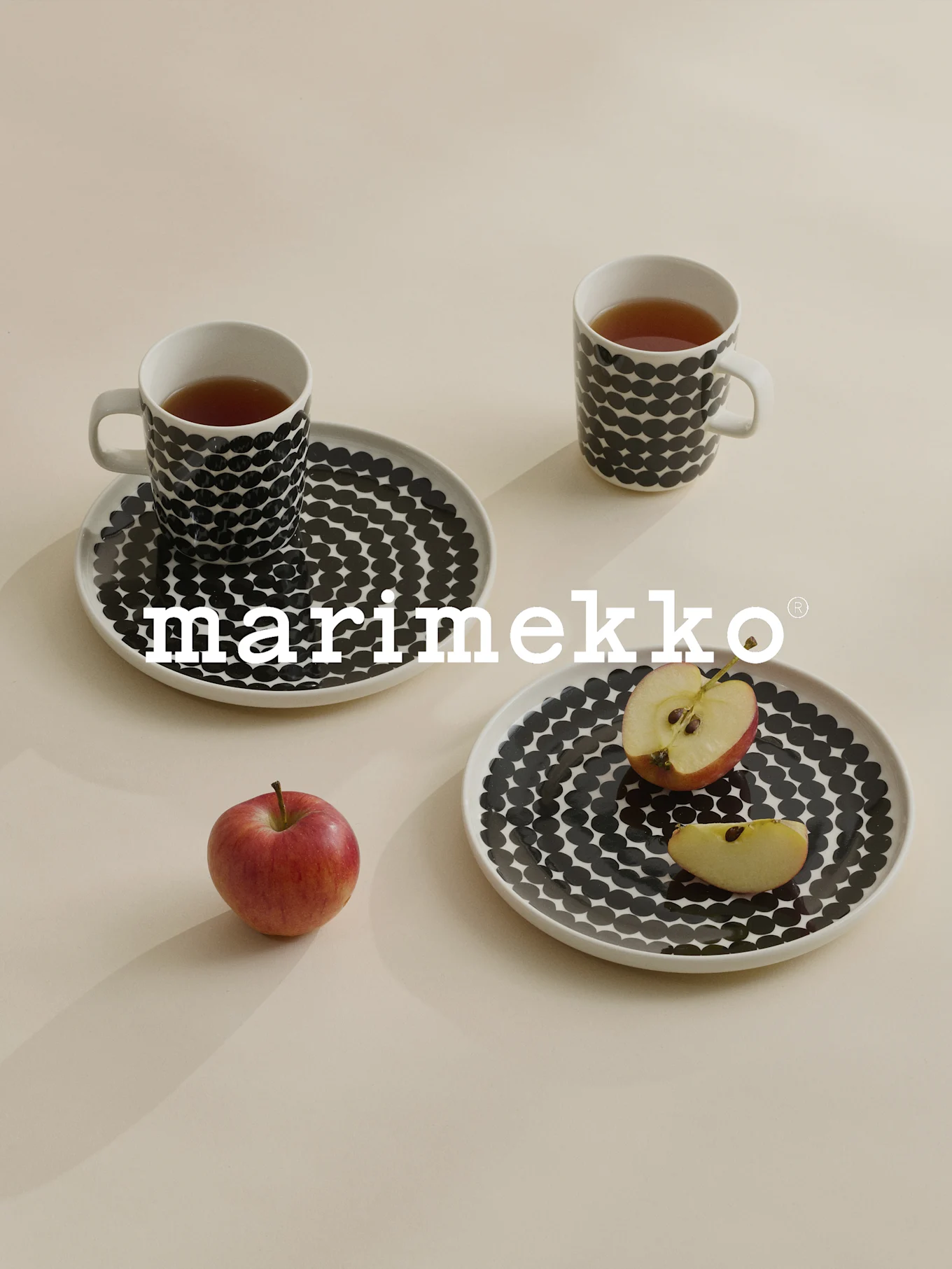 Deux tasses et assiettes à pois noirs, thé, pomme rouge, logo Marimekko.