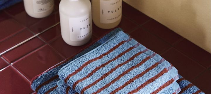 Les motifs tels que les rayures et les carreaux constituent l'une des tendances intérieures de l'automne 2025. Ici, les serviettes rayées rouges et bleues de la collection Drift de Scandi Living sont posées sur une étagère à carreaux rouges.
