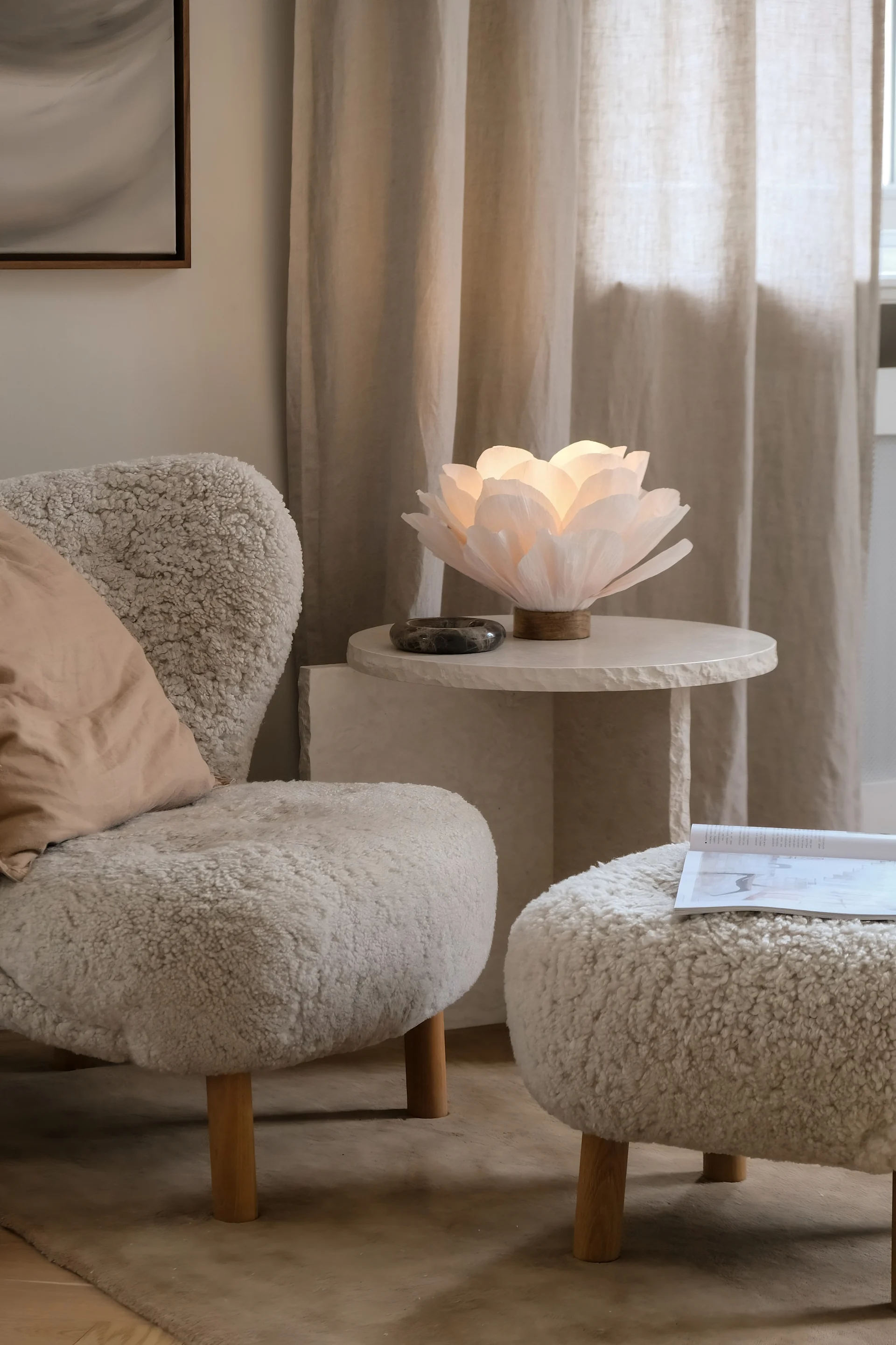 Un salon aménagé dans des tons beiges, avec un fauteuil Little Petra et une table basse en marbre, décorée avec la lampe de table Lisa de Watt & Veke.