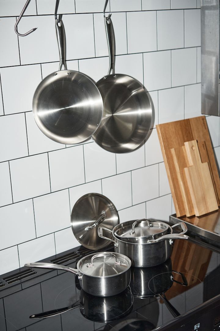 Des poêles propres de Nordwik sont suspendues dans une cuisine carrelée, des casseroles de Nordwik sont posées sur la cuisinière en dessous.