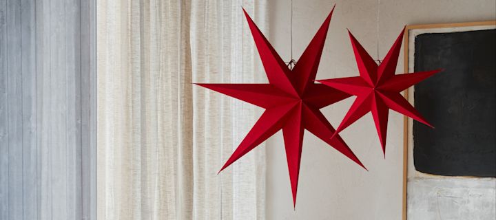 Deux lanternes en papier rouge en forme d'étoile de Watt & Veke suspendues dans un salon. 
