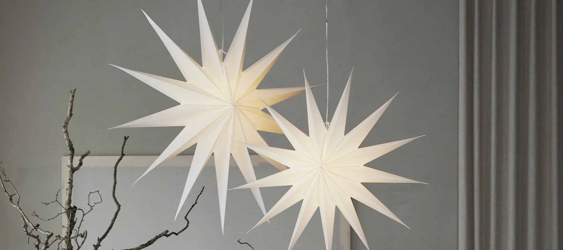 Deux lanternes en papier rouge en forme d'étoile de Watt & Veke suspendues dans un salon. 