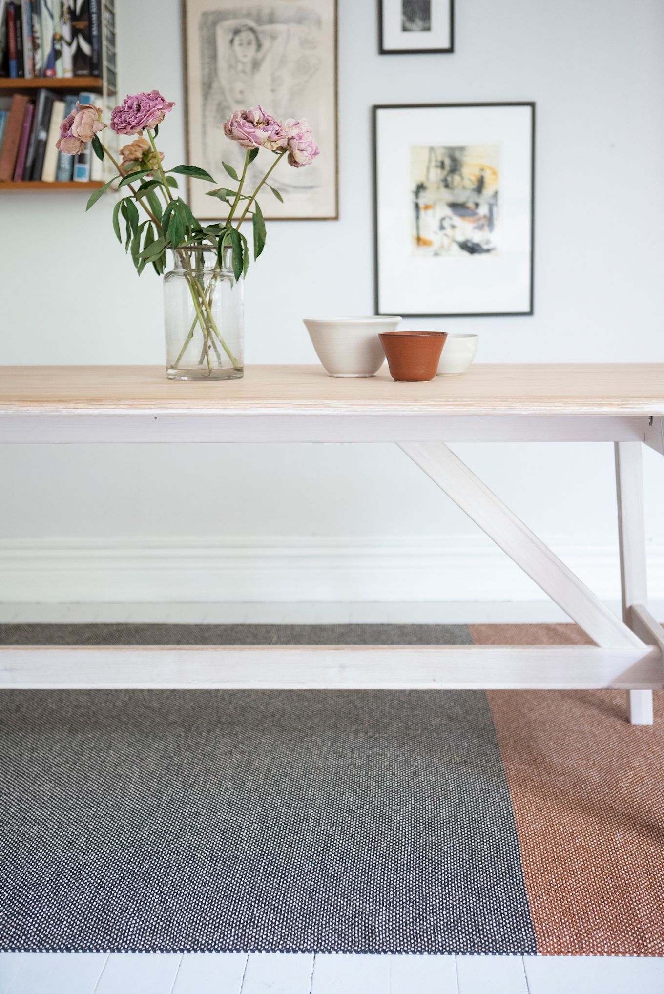 Tapis pour l'entrée : le tapis Moor de Brita Sweden est placé sous une table, au mur de nombreux tableaux.