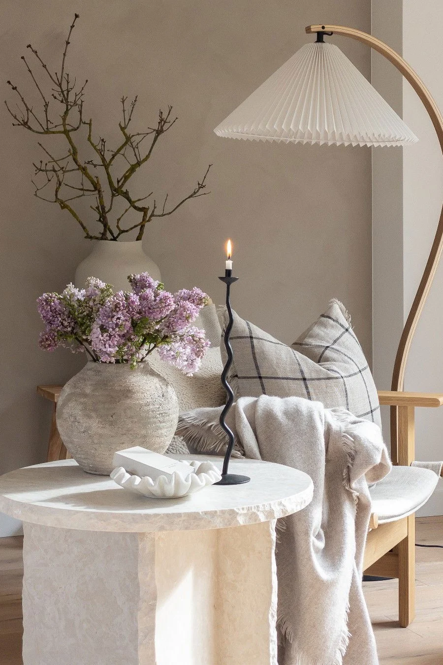 Une table basse en marbre, décorée avec des fleurs, une coupe et un bougeoir, le tout dans un style rustique.