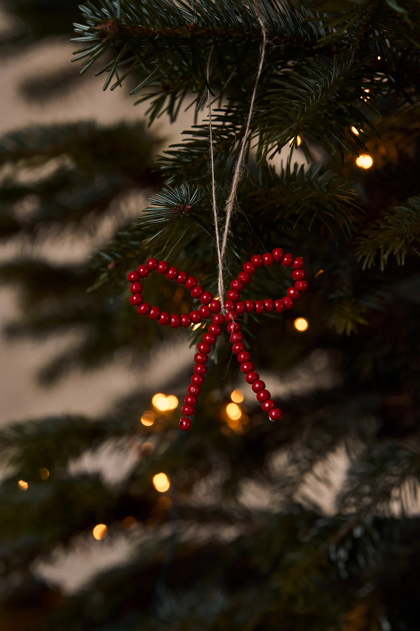 Couronne de Noël avec un grand nœud en velours rouge sur une porte en bois rouge vieillie avec des branches de pin givrées.