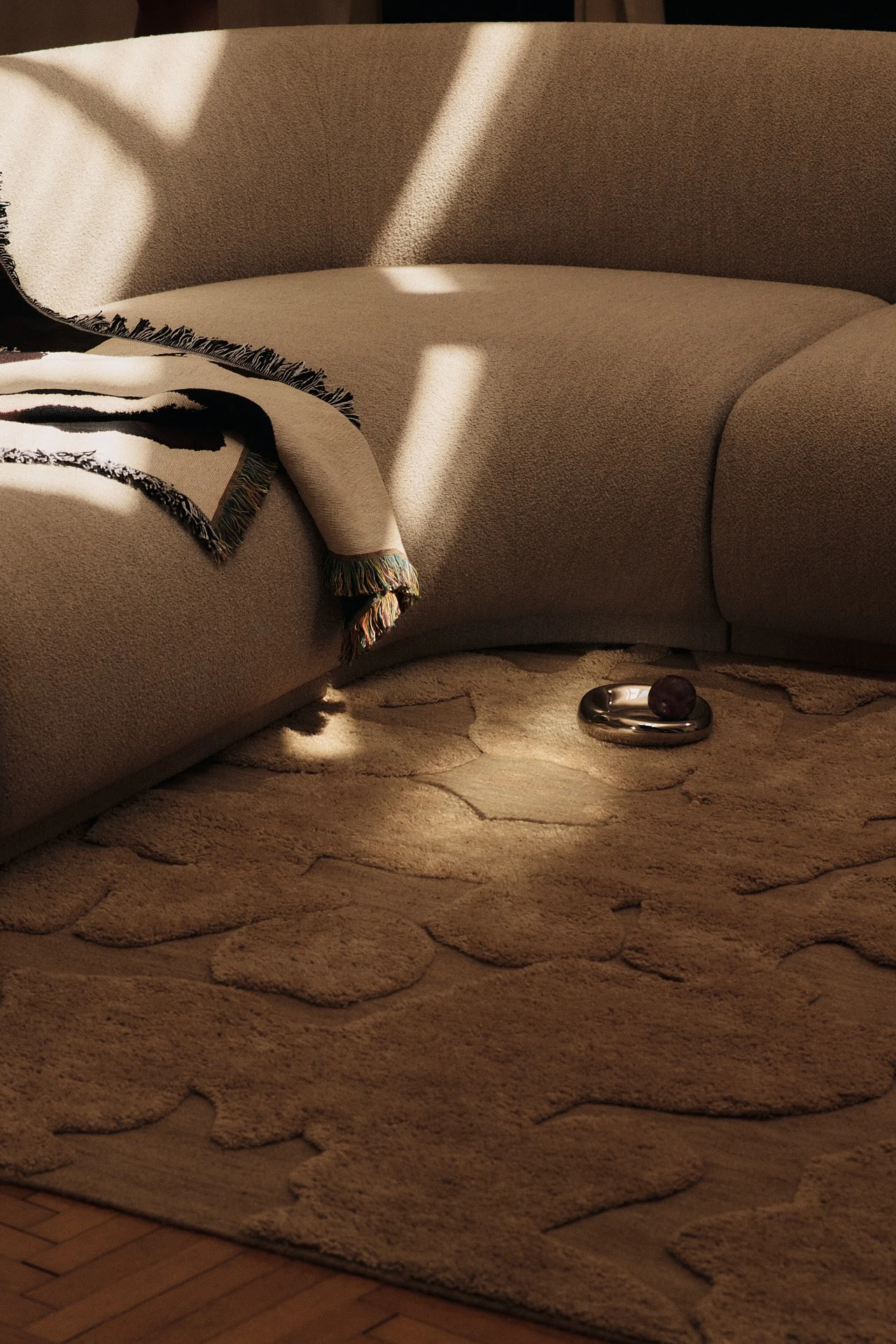 Les tendances couleurs de l'année 2026 se reflètent dans ce salon, où des meubles brun clair sont associés à un tapis inspiré des années 1960 dans une teinte kombucha.